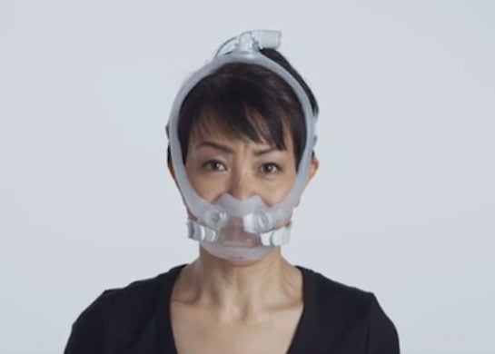 Una mujer usa la mascarilla AirFit F30i de la marca ResMed