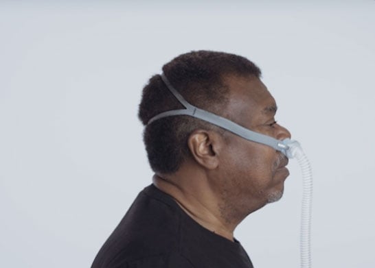 Un hombre usa la mascarilla AirFit N30i de ResMed mientras viste una camisa negra