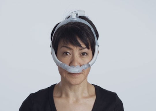 Una mujer usa la mascarilla AirFit P30i de la marca ResMed y viste una camiseta negra