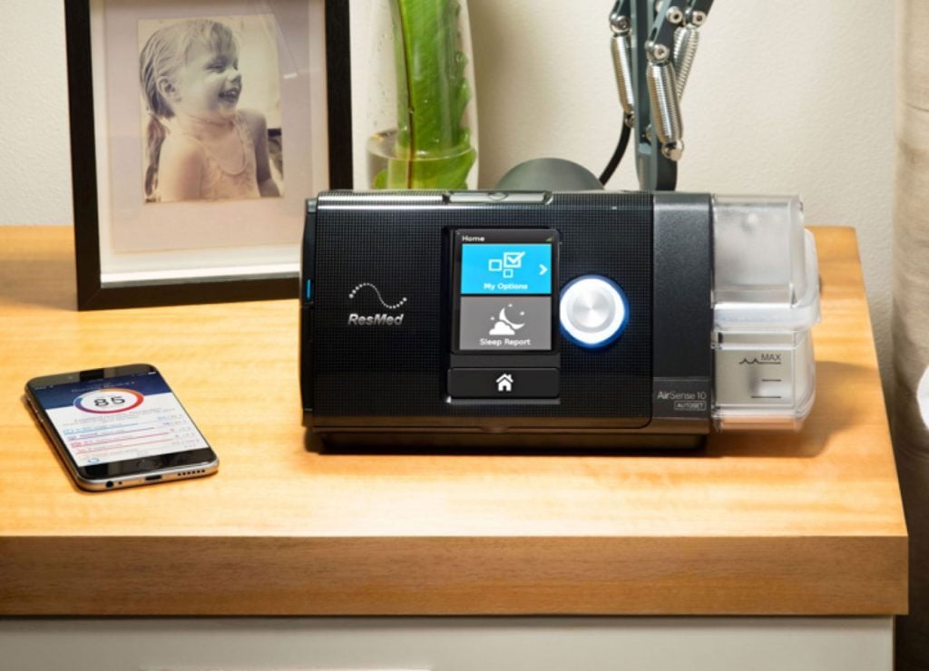 Equipo AirSense 10 y un celular con la aplicación sobre una mesa