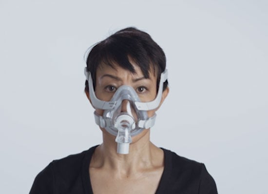 Una mujer usa la mascarilla femenina AirTouch F20 de ResMed